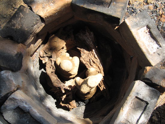 Die Figuren werden auf bereits gluehende Asche gestellt und mit Mangoholz umschichtet. Das Ei mit dem Metall drin schaut nach unten.