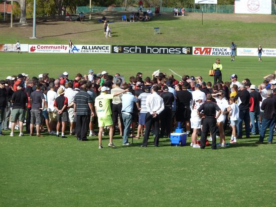 Viertelspause, mitten drin sind etwa 30 Spieler und der Coach.