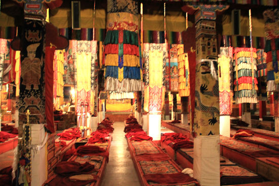 Kloster Ganden - Mein erstes Foto in einer großen Versammlungshalle, wie es in jedem der tibetischen Klöster zum teil auch mehrere gibt. Trotz aller Unterschiede sind sie im Grundaufbau gleich und auch die Gestaltung der Farben und Stoffe ist ähnlich.