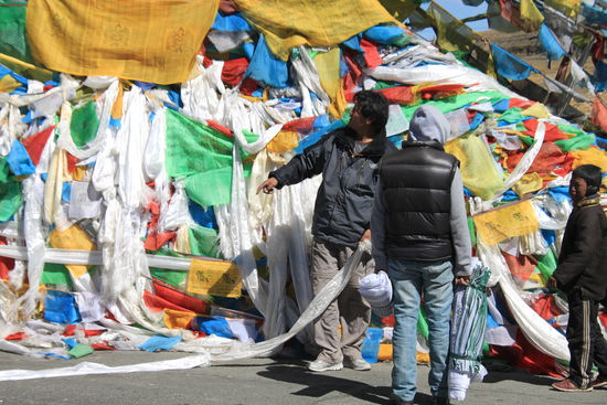 Hier am höchsten Pass unserer Reise hängen auch unser Fahrer und unser Guide ein Band mit Gebetsfahnen auf. Anders als unsere kleinen "Fähnchen" die wir erstanden haben, haben sie ein Seil dabei das mindestens 15-20 Meter lang ist und an das wir uns mit vereinten Kräften hängen, um es spannen zu können.