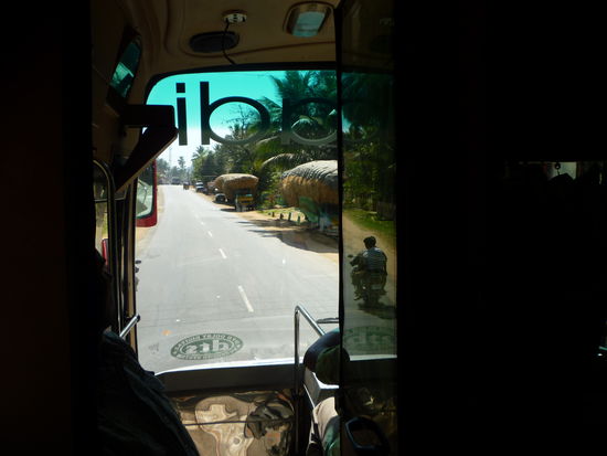 Blick durch die Frontscheibe des Busses auf die hoch beladenen Wagen mit Heu.