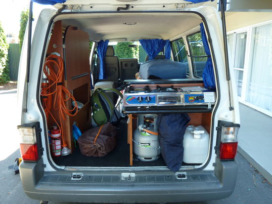 Ausstattung: Links: Stromadapter fuer  Campingplaetze mit Lademoeglichkeit, Lampe mit Haken fuer den Einsatz ueberall, ausklappbarer Tisch mit Stauraum, darunter weiterer Stauraum fuer Getraenke und Klamotten, Gasherd mit 2 Kochfeldern samt Grill.