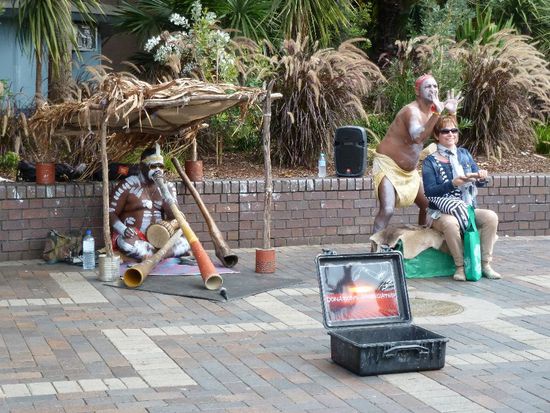 Hochgradiges Fremdschähmen: "original" Australische Ureinwohner spielen ihr Didgeridoo zu harten Elektrobässen und eine Klischeetouristin klopft die Klanghölzer...aua!!!