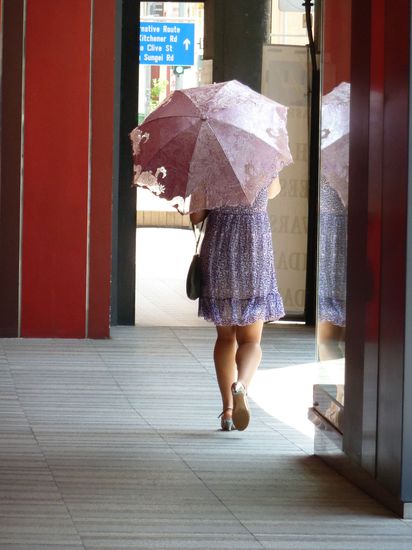 Teintbedachte Chinesin mit UV-resistentem Schirm