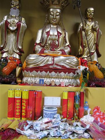 Hier fehlt zur Zeit die Spendenbox und so werden die Gaben eben einfach vor der Statue auf dem Tisch deponiert - und hier sind nicht wenige rote 100 RMB Scheine (Chinas grösster Banknote, entspricht etwa €12) darunter.