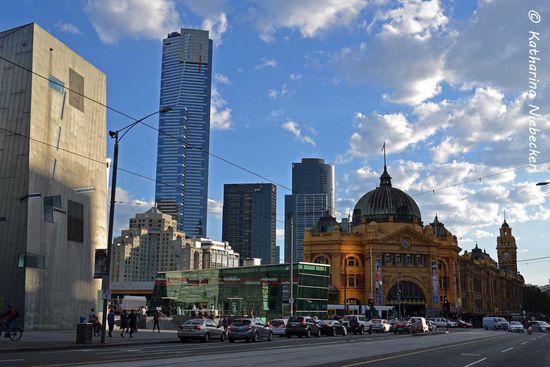 Dem Federation Square gegenüber liegt die Flinders Street Station, mit den Hochhäusern von "South Yarra" im Hintergrund.