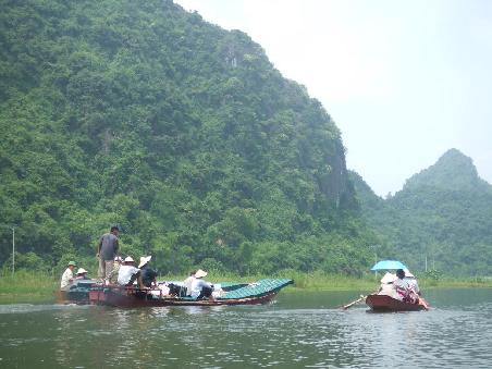 Der Weg zur Parfuempagode, dem groessten Heiligtum der Buddhisten in Vietnam, fuehrt nur uebers Wasser. Links wird das Dach fuer die Seilbahnstation transportiert und rechts ein paar Touristen.
