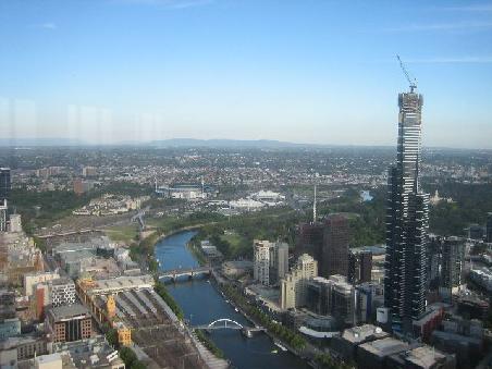 Aussicht vom Observation Deck (das hoechste Gebaeude auf der Suedhalbkugel) auf Federation Square, Flinders Street Station und im Hintergrund der Melbourne Cricket Ground.