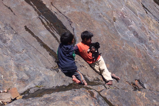 Kinder trinken das Wasser aus den Felsen