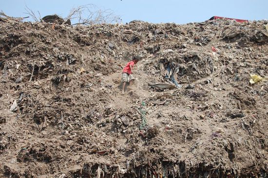 Ein barfüssiger Junge klettert vom rund 10 m hohen Müllberg
