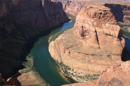 Und dann kommen wir an den Rand der Schlucht.
Wie ein blaugrünes Band legt sich der Colorado River um den roten Fels.