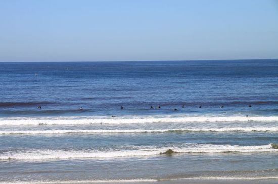 Die schwarzen Punkte im Wasser sind die Köpfe der Surfer.
Diese hängen mit ihren Brettern im Wasser und warten auf die perfekte Welle.
Wenn die kommt, springen sie auf ihr Brett und machen auf der Welle die tollsten Drehungen und Sprünge.
Es macht Spaß zuzuschauen, man sieht gut wer was kann und wer besser noch ein bisschen üben sollte.
