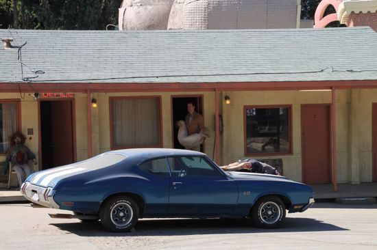 Dann geht die Tür am Motel auf und Norman Bates kommt mit einer ermordeten Frau auf dem Arm heraus, er will sie in seinen geöffneten Kofferraum legen.