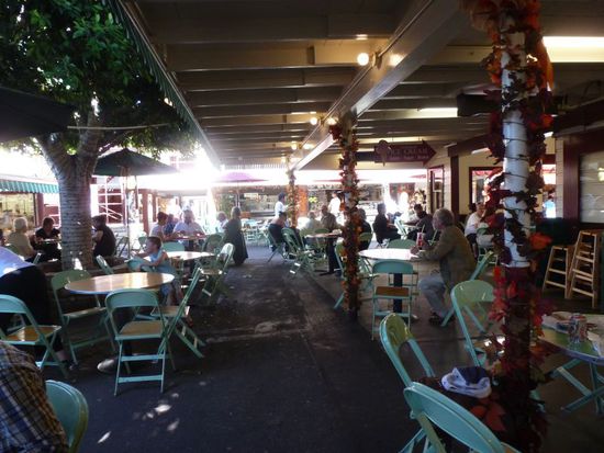 Wenn man sein Essen am Stand geholt hat, geht man mit seinem Tablett an einen der vielen Tische die hier im Schatten und Vordächern und Bäumen aufgebaut sind.
Es ist wirklich ein schöner Ort um eine Mittagspause einzulegen, besonders da die Temperatur jetzt schon locker auf über 40 Grad angestiegen ist!