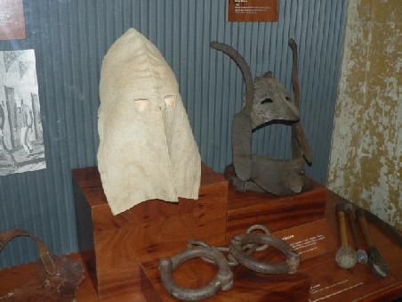 Eiserne Maske (rechts hinten), Fussfesseln (links vorn), sowie Knueppel (rechts vorn)