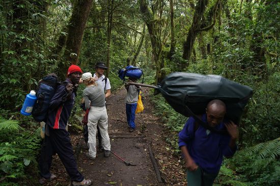 Endlich geht es los. Die Traeger duerfen offiziell nur 20 Kilo tragen, doch oft ist es das Doppelte, was sie auf Ruecken, Nacken und Kopf den Berg hoch schleppen. In der roten Muetze: Abdallah, unser Koch, dahinter Anne und Dominik, die ganz langsam gehen muessen, weil Dominik sehr schwach auf den Beinen ist.