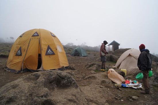 Als wir ankommen, stehen die Zelte schon. Und Kayembe ist schon dabei, uns warmes Wasser zum Waschen zu bringen