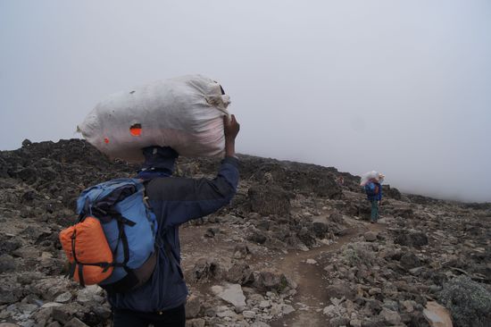 Die wahren Helden des Kilimanjaro: die oft schlecht ausgerüsteten, miserabel bezahlten Helfer, die teilweise 40 Kilo die steilen, steinigen Wege hochwuchten