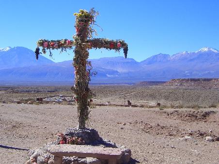 Ein mit Papierblumen geschmücktes Kreuz in der Wüste