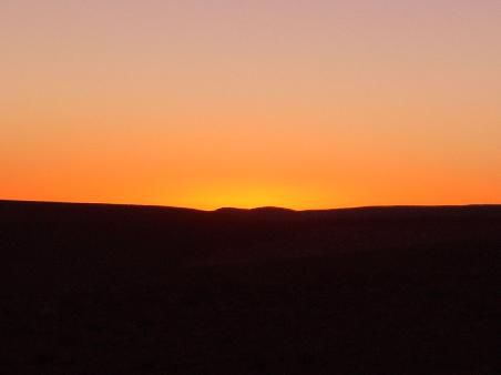 Im Westen strahlen die letzten Sonnenstrahlen über die Kuppeln der Berge