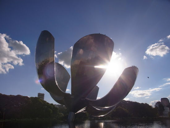 Riesenmetallbluete in einem Park, die abends von innen bunt beleuchtet wird