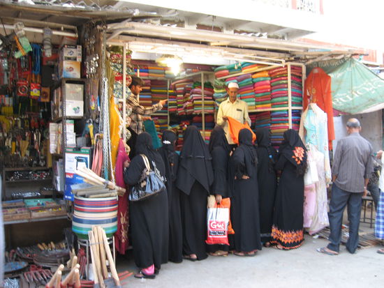 Muslimische Frauen, welche bunte Saris begutachten