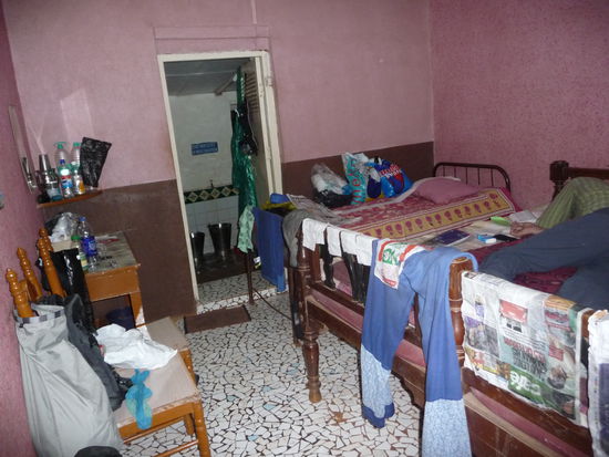 Das Zimmer des Guesthouses Hope Hall. Sehr schoener Boden aus Kacheln-Stuecken. Unsere klitschnassen Sachen haben wir ueberall zum trocken aufgehaengt. Man beachte erschoepfter Olaf rechts auf dem Bett...