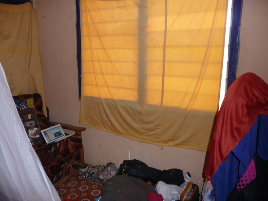 mein Zimmer mit einem großen Bett, einem Sessel und auf dem Bild rechts ist ein Ventilator, den ich zum Trocknen meiner Handtücher mißbrauche. Dahinter steht ein kleines Tischchen.