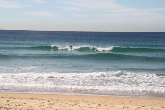 Zahlreiche Surfer und Schwimmer im Wasser.Die Wellen kommen hier sehr schön ruhig und gleichmäßig. Teilweise kamen die Leute barfuß aus ihren gegenüberliegenden Appartements über die Straße zum Wasser