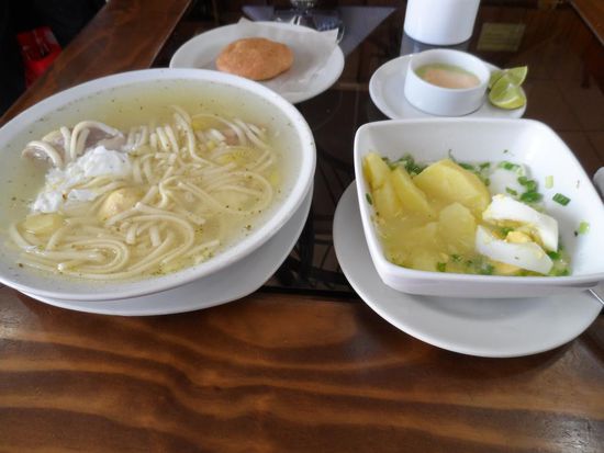 Fruehstueck (links: Nudelsuppe mit Ei und Huhn, rechts: Kartoffel und Ei in einer Zitronensauce, im Hintergrund: Brot und eine ziemlich scharfe Chillisauce)
