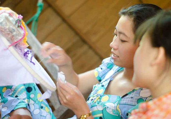 hier zeigt die junge Mutter, wie sie mit Sticken ihren Lebensunterhalt verdient.