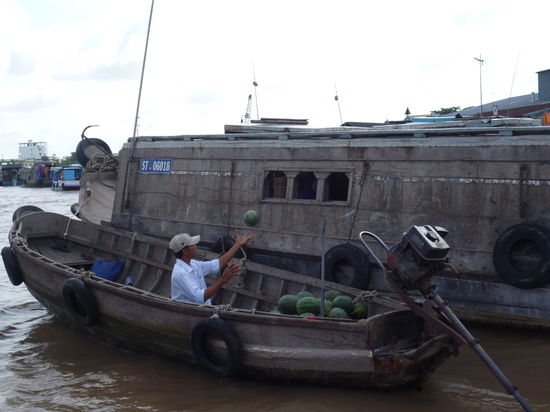 Mit viel Schwung werden kiloweise Wassermelonen von einem Boot zum anderen verfrachtet.