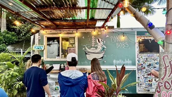Nach einiger Suche landen wir auf einem Platz mit jeder Menge „Food-Trucks“
Diese Food Trucks sind auf Hawaii die günstigere Möglichkeit zu essen—hier gibt es „Poké Bobs“—das ist etwas japanisch angehaucht, mit klein geschnittenem rohen Fisch