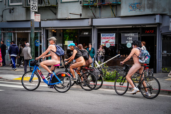 Krass—vor einem Bikerlokal tummelt sich eine große Gruppe nackter Personen-die später per Rad durch die Straße fahren