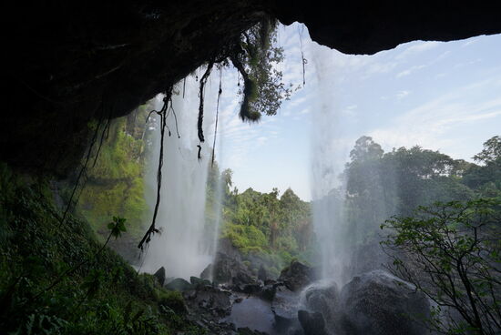Wir können sogar hinter den Wasserfall in eine kleine Höhle gehen. Hier wurden früher die Tiere zum Schutz vor Feinden gehalten.
