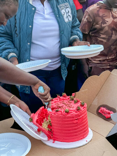 Gloria überrascht mich noch mit einer Torte!
Ich probiere—sie ist lecker! Aber zu viel! Also wollen wir sie auch noch verteilen.
Das artet leider aus. Es gibt fast Prügeleien, als Gloria die Torte verteilen will—so stoppen wir nach der Hälfte und ich nehme sie erstmal mit