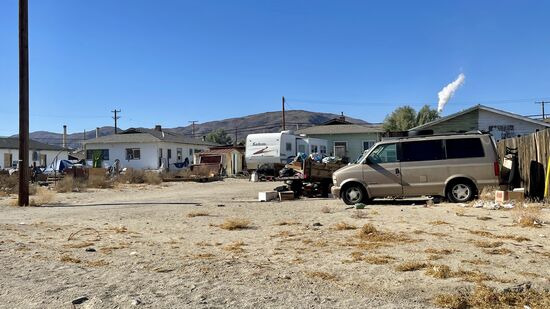 Flache Autowracks, Industrieschrott und rostige Fahrzeuge aller Art, neben verlassenen Häusern