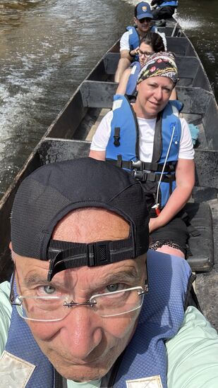 Im hinteren Bereich sitzt der Mann am Motor, vorn der Steuermann, der das Boot mit einem großen Stab geschickt um Steine, Wurzeln und Sandbänke steuert