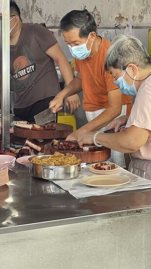 …im Rekordtempo wird hier Fleisch mit Schwarte (Schwein??)gehackt, auf Teller angerichtet und verkauft