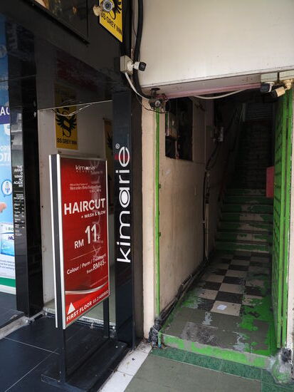 Man wird angelockt mit dem Preis von 11 MYR für Schnitt und waschen…die Treppe müssen wir erklimmen und stehen erstmal vor einer verschlossenen Glastür—durch die ich aber eine Dame am Empfangsthresen stehen sehe—und als ich auf Thomas deute und zu verstehen gebe, dass es nur um seinen Kopf geht, öffnet sie uns doch die Tür