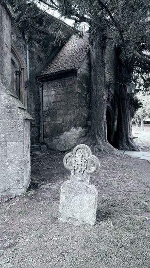 Der atmosphärische alte Friedhof bei der Kirche mit einem alten Grabstein mit einer aufwendigen Verzierung in Form eines Kleeblatts