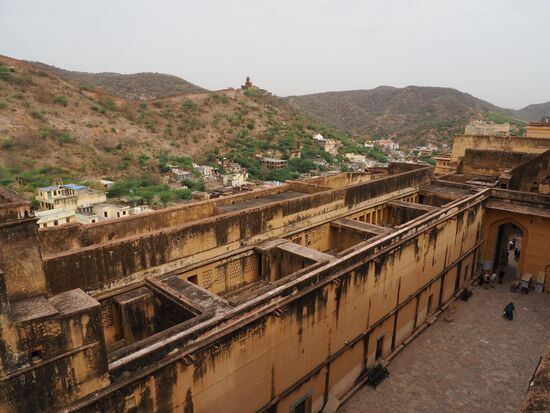 Die dicken Mauern und Wehrgänge der Festung und im Hintergrund die trockene Hügellandschaft des Aravalli-Gebirges
Auf den Hügeln gegenüber sieht man weitere Verteidigungswälle, die oft als drittlängste Mauer der Welt bezeichnet wird