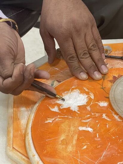 Die große Marmorplatte wird eingefärbt, damit man vorzeichnen kann und das besser sieht. Dann wird das Motiv sorgfältig ausgearbeitet. Anschließend die kleinen Teile eingelegt.