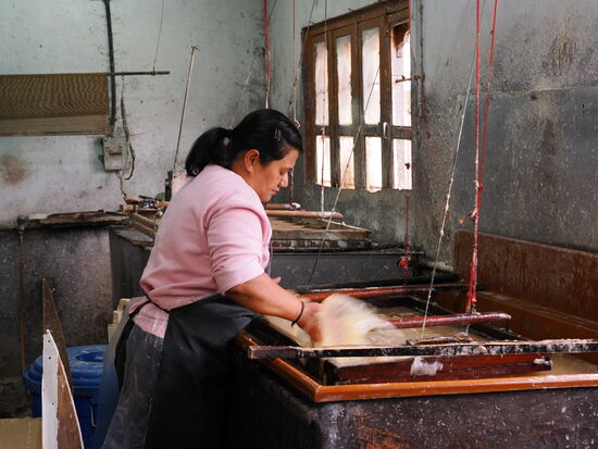 Zwei weitere Frauen sind dann dafür zuständig dünne Lagen des Breis mit Hilfe eines Siebs im Holzrahmen abzutrennen und zu pressen. Diesen Vorgang nennt man „schöpfen“