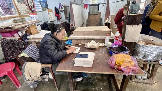 Die Dame hier hat einen ruhigen Job: sie faltet und schneidet sorgfältig Briefumschläge