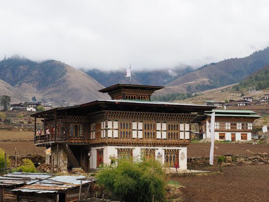 Die Häuser hier zeigen den traditionellen bhutanischen Baustil mit aufwändig verzierten Holzfensterrahmen und flachen Dächern