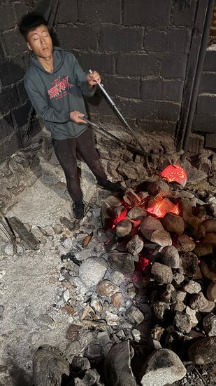 Nach dem Bad schauen wir uns die Angelegenheit genauer an: Hier im Feuer werden die dicken Flussteine erhitzt- sie setzen dem Wasser heilende Mineralien zu