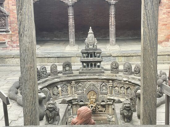 Das Steinbecken ist kunstvoll gestaltet mit 72 fein geschnitzten Steinreliefs von tantrischen Gottheiten und wird von Steinschlangen gesäumt