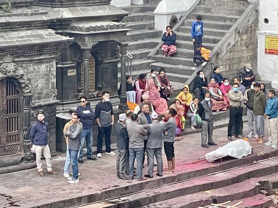 Rechts unter dem weißen Tuch liegt ein Verstorbener, dessen Feuerbestattung gerade vorbereitet wird