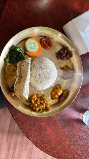 Dal Bhat ist eine reichhaltige Mahlzeit die typischerweise auf einem Metallteller angerichtet wird:
Ein großer Berg aus gekochtem Reis (Bhat) in der Mitte.
Dal ist eine Linsensuppe die in einer extra kleinen Schale serviert  wird
Dazu gibt es verschiedene Gemüsecurrys und gedünstetes Blattgemüse
Und das knusprige Papadum—welches ich besonders gern mag!
Für 4 Personen haben wir knapp 15 Euro bezahlt